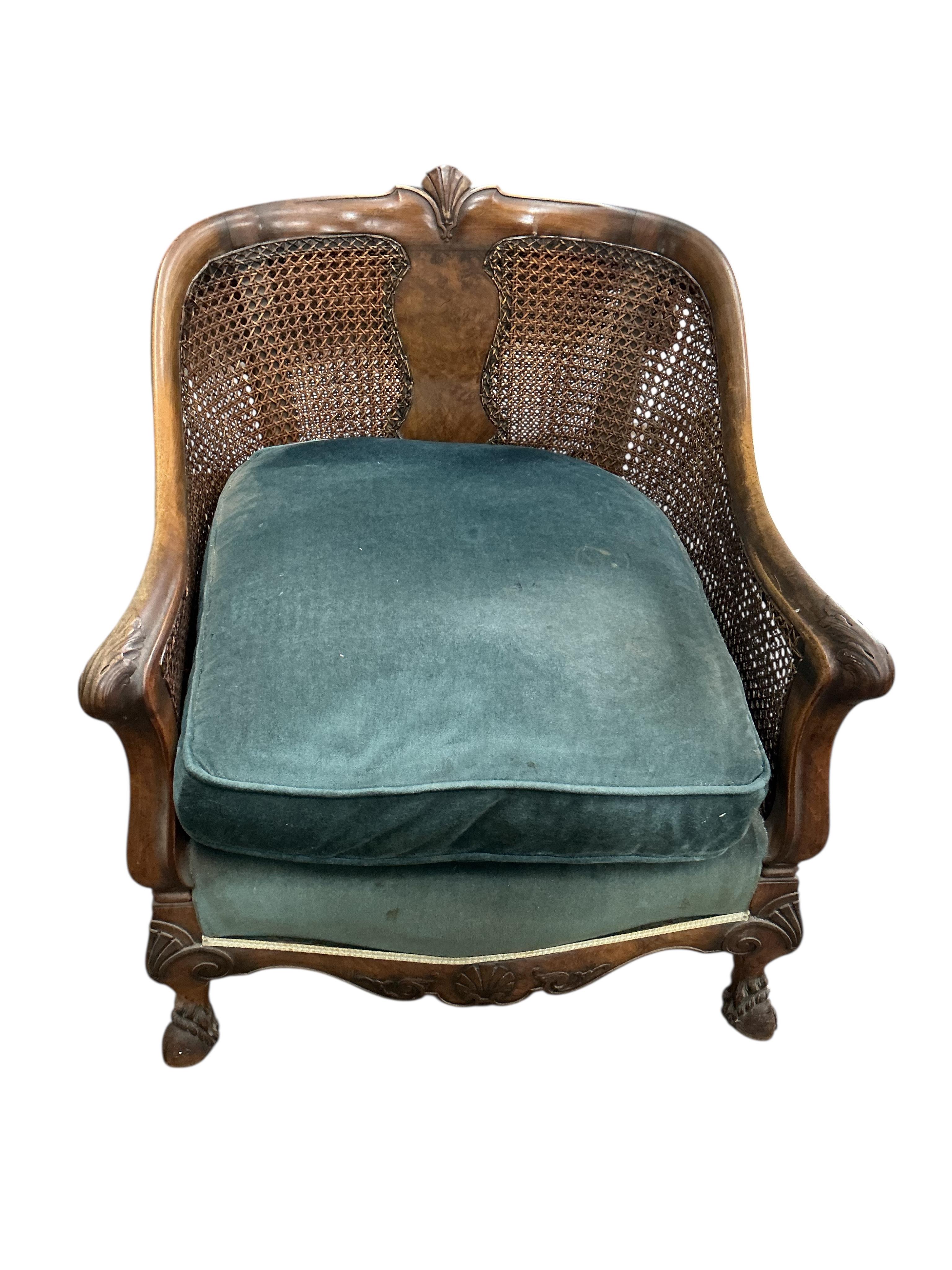An early 20th century carved walnut and double canework three piece bergère suite, cane in need of repair